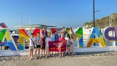 Group of students holding a the VT flag  stand in front of large letters that spell Panama. A harbor is in the background. 